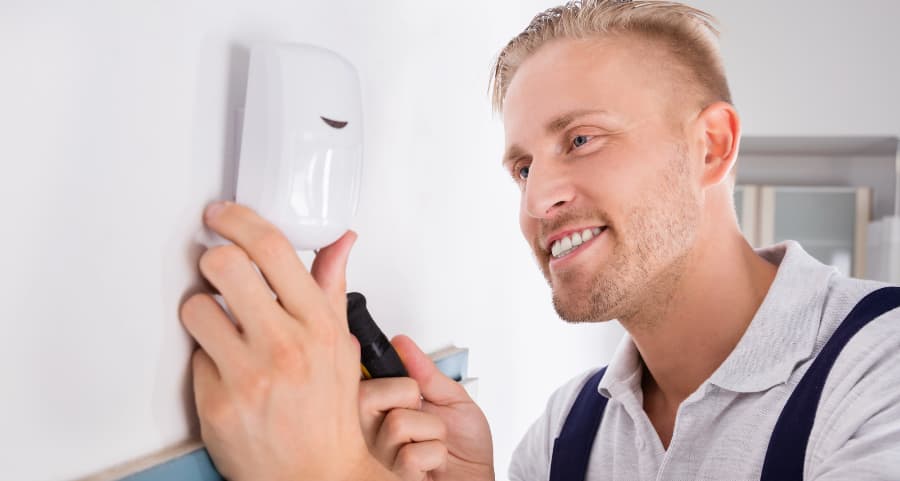 Man installing a motion sensor inside a home